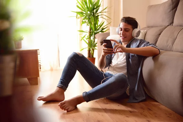 Tini szót használ egy okostelefon, nappaliban ül — Stock Fotó