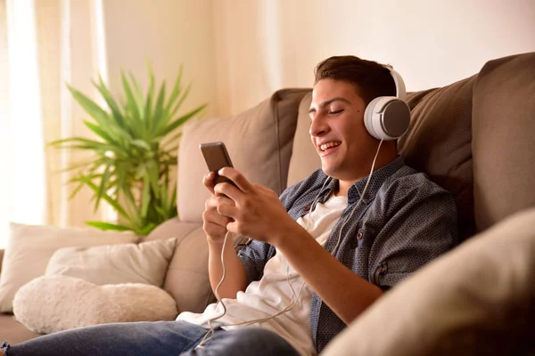 Teenager ved hjælp af en mobiltelefon med hovedtelefoner sidder - Stock-foto