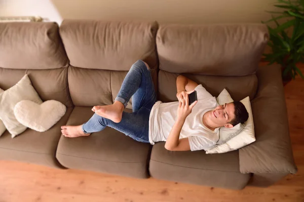 Fiatal fiú kanapén egy smartphone felső nézetében — Stock Fotó