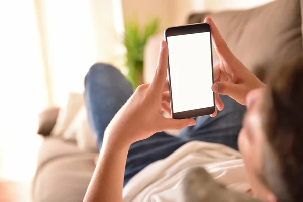 Genç adam izlerken multimedya içeriği yatan bir smartphone cep telefonu ile bir
