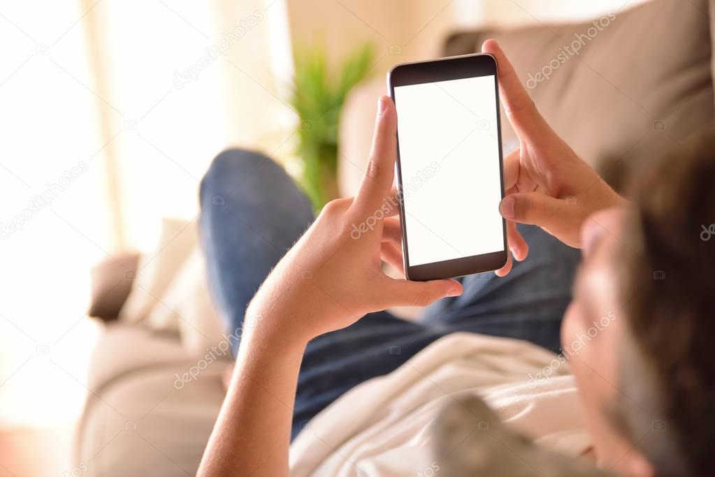 Young man watching multimedia content on a smartphone lying on a