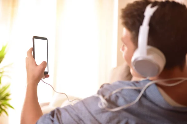 Tinédzser látszó-on a mobil és a hallgató-hoz zene mögött — Stock Fotó