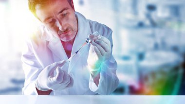 Şırınga ve flakon bir masanın arkasında elinde olan bilim adamı