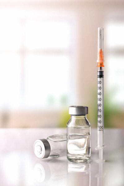 Флаконы и шприц на белом столе с фоновыми окнами vertica
