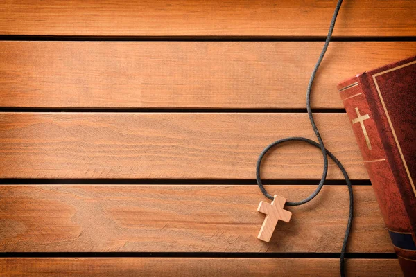 Biblia con colgante en forma de cruz sobre tabla de listones de madera — Foto de Stock