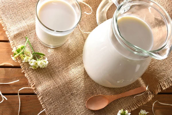 Glass and jug with milk on wooden table outdoor top — Stock Photo, Image