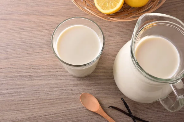 Verre de lait et cruche sur plateau en bois — Photo