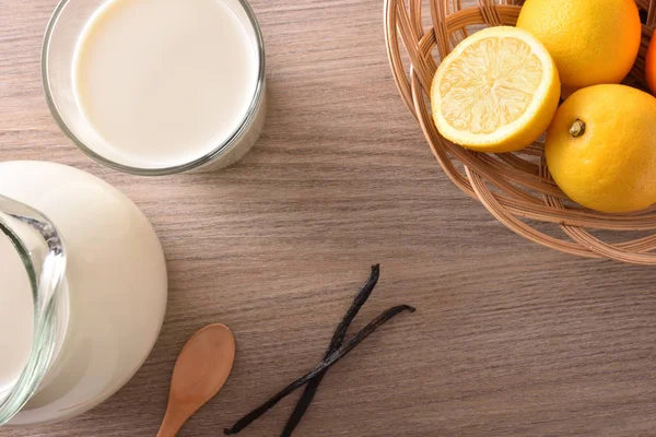 一杯牛奶在木桌上柠檬和肉桂顶部 — 图库照片