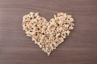 Ahşap masa üzerinde patlamış mısır ile yapılan kalp. Sinema seven kavramı. Üstten Görünüm