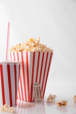 Beyaz arka plan üzerinde ferahlık, patlamış mısır ve film bilet ile sinema anlar kavramı. Dikey kompozisyon. Önden Görünüm.