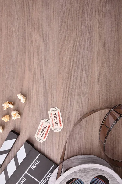 Equipment and elements of cinema on wooden table. Concept of watching movies. Vertical composition. Top view.