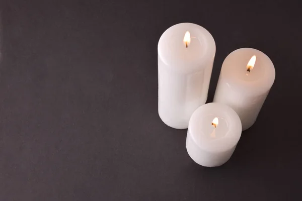 Tre candele accese su sfondo grigio degradante vista dall'alto — Foto Stock
