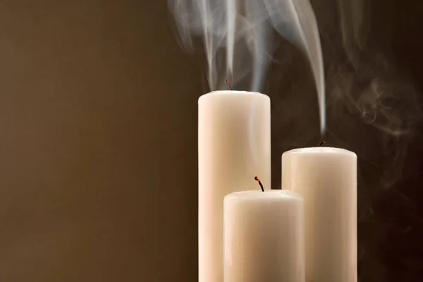 Three candles newly extinguished on bown background front — Stock Photo, Image