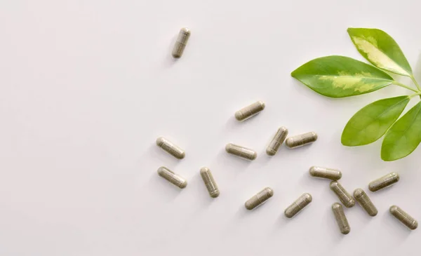 Background with capsules and plant on white table top view — Stock Photo, Image