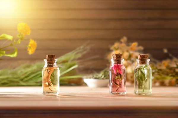Üvegek növényi esszenciával az asztalon és a fa háttér előtt — Stock Fotó