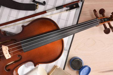 Öğrenci keman ve klasörü ahşap masanın üstünde sopaları var.