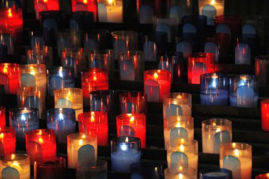 Birçok kırmızı, sarı ve mavi ayin mumları bir kilisedeki istekler için yakıldı. Manzara yükseldi. Yatay bileşim.