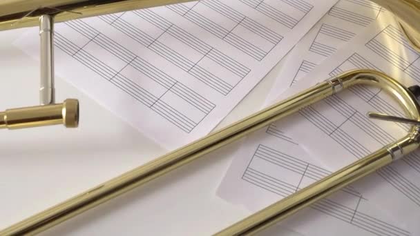 Hand leaving trombone mouthpiece on blank sheet music on table. — Stock Video