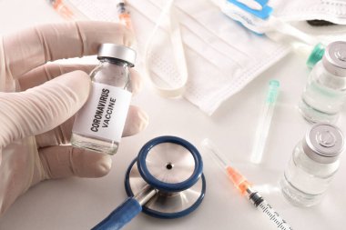 Doktor elinde kovid 19 virüsüne karşı aşı var. Masada tıbbi materyaller var. Üst Manzara. Yatay bileşim.