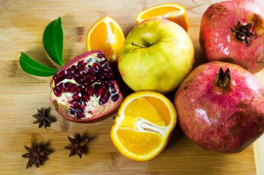 Meyve dolu bir hayat. Garnet tahtada kesiliyor. Portakal, mutfak tahtasına çizilmiş..