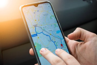 Şoför haritada telefonla geziniyor. Telefonda Europa 'nın bir haritası açık. Telefon arabadan şarj oluyor..