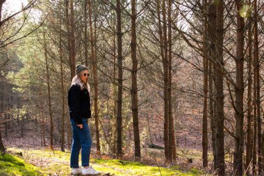 Gözlüklü bir kız sabah ilkbahar ormanında yürür. Bahar ormanında sabah.