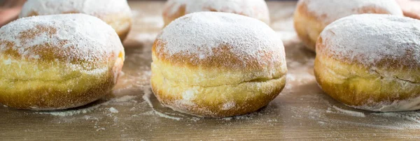 Do-it-yourself donut cooking. Donuts lie on a wooden table. Fresh hot donuts on a saucer.