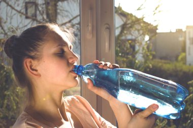 Karantinada spor yaparken su içen bir kız.