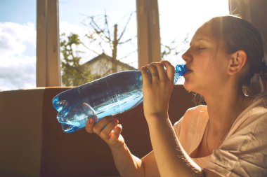 Karantinada spor yaparken su içen bir kız.