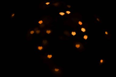 Siyah arkaplandaki kalplerin turuncu ışıkları.