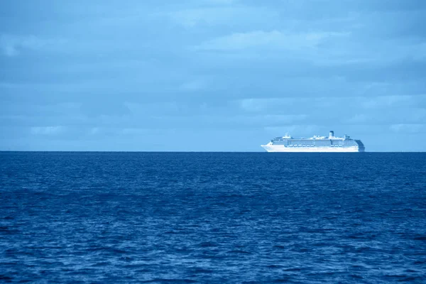 Zeegezicht met een eenzaam schip in de trendy klassieke blauwe kleur van het jaar. — Stockfoto