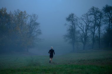 Runner in grey autumn misty morning, active life even in bad weather clipart
