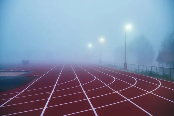 Zdjęcie koncepcyjne ciężarówki i pola. Czerwony tor lekkoatletyczny we mgle. Bieżące zdjęcie, białe miejsce do edycji — Zdjęcie stockowe