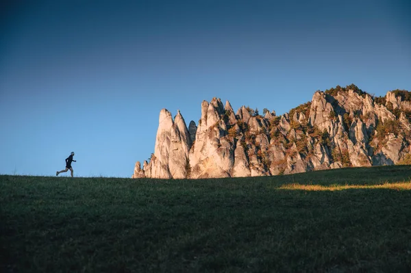 Corredor en un paisaje inusual. Silueta de atleta en el horizonte y colinas rocosas en el fondo — Foto de Stock