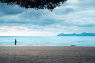 Boş kumsalda yalnız bir kadın. Depresyon, üzüntü, melankoli konsepti fotoğrafı
