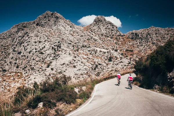 Man and woman ride together on road bicycle. Adventure in big mountains — ストック写真