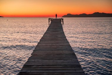 Sahildeki iskelede bir kadın silueti