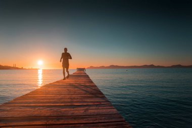 Sabah koşan tren. İskele, deniz, arka planda gün doğumu