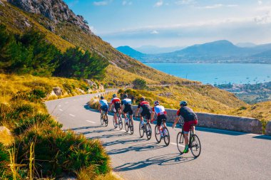 Gün batımında bisiklet süren sportif arkadaşlar deniz kenarında güzel doğada. Sahilde yol bisikleti. Doğa sporu arka planı. Takım çalışması konsepti fotoğrafı