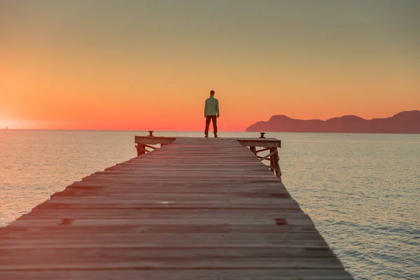 부두에 혼자 서 있는 남자. 뒤에 보이는 여름 일몰 하늘. — 스톡 사진