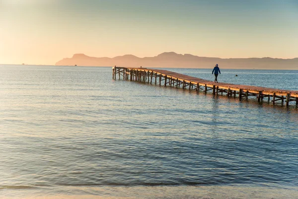 Frau, die allein auf der Seebrücke am Meer im warmen Sonnenuntergang spaziert. Konzeptfoto von Einsamkeit — Stockfoto