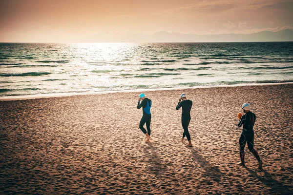 Tre partecipanti al triathlon che camminano sulla spiaggia prima dell'allenamento di nuoto. Maiorca, Spagna — Foto Stock