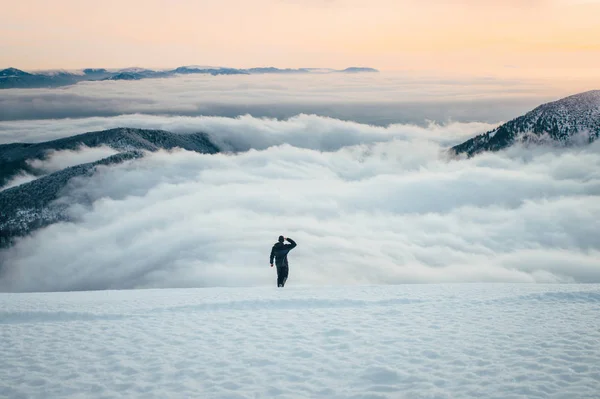 Man in hilly winter landscape looking at the valley