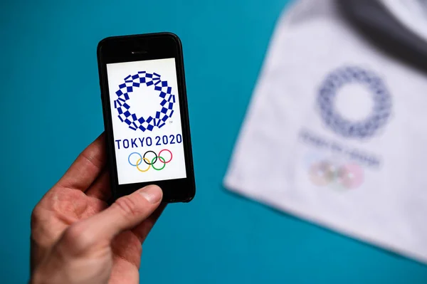 TOKYO, JAPAN, JANUARY. 20. 2020: Smartphone și Tokyo 2020 logo-ul jocului olimpic de vară. Aplicație olimpică fotografie conceptuală, spațiu de editare albastru — Fotografie, imagine de stoc