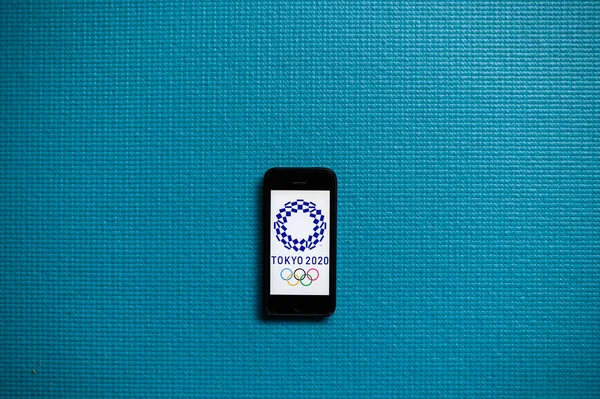Tóqueo, JAPÃO, JANEIRO. 20 anos. 2020: fundo olímpico azul. Logotipo dos XXXII Jogos Olímpicos de Verão 2020 em uma tela do telefone móvel . — Fotografia de Stock