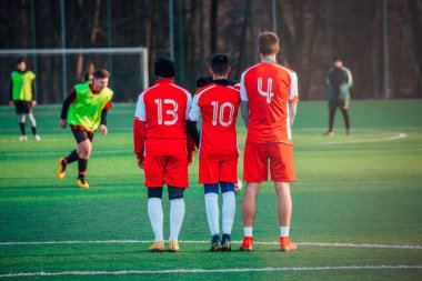 Futbol serbest vuruşu, futbol konsepti fotoğrafı, kırmızı formalı oyuncular, yeşil çimen gün batımı ışığı