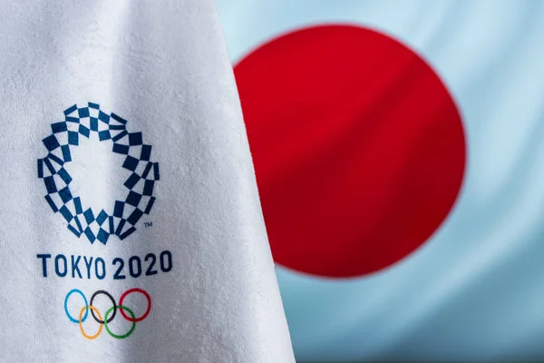 ТОКИО, ЯПОНИЯ, ФЕВРАЛЬ. 714. 2020: Олимпийский логотип Токио 2020, размахивающий японским флагом на заднем плане — стоковое фото