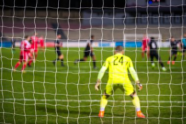 Futbol kalecisi, arka planda futbol maçı.