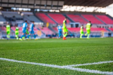 Futbol fotoğrafı, yeşil çimen, arka planda bulanık futbol oyuncuları ve stadyum