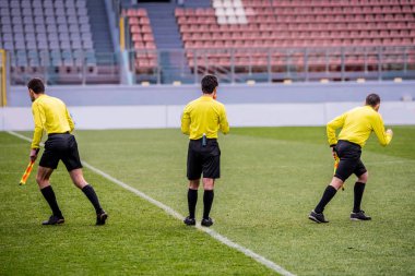 Tree referees at soccer stadium before football match clipart